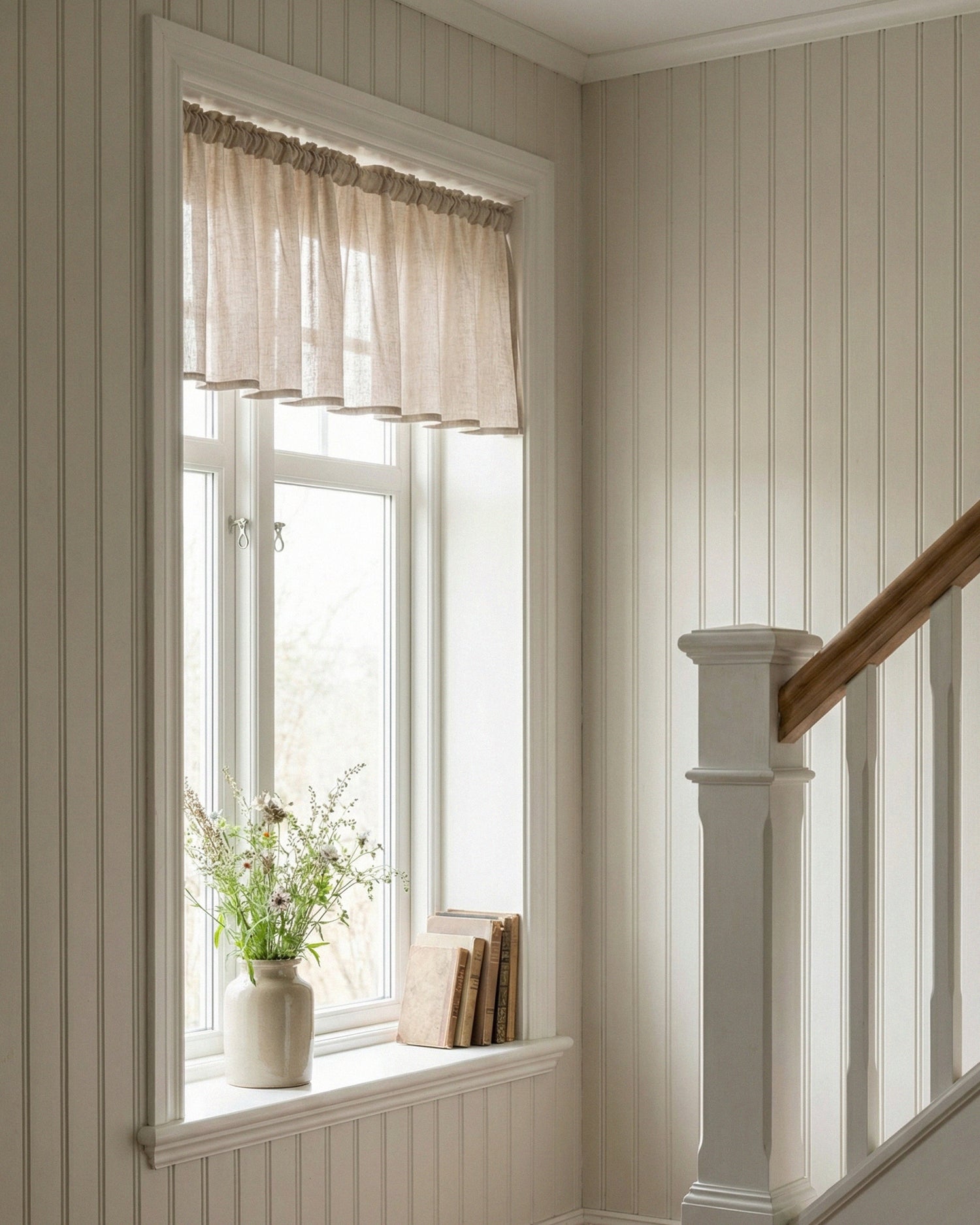 Beige gardinkappa monterad i nisch i ett fönster i en halltrappa