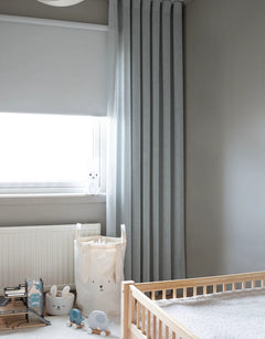 Mörkläggande vit rullgardin och blå gardin i barnrum