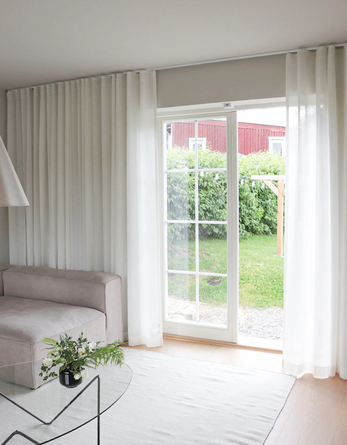 Vita skira gardiner i ett vardagsrum framför altandörr